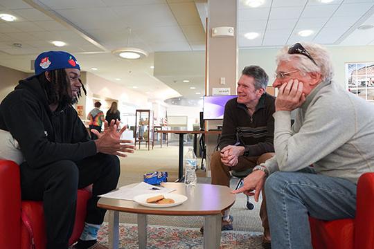 three men talking at table