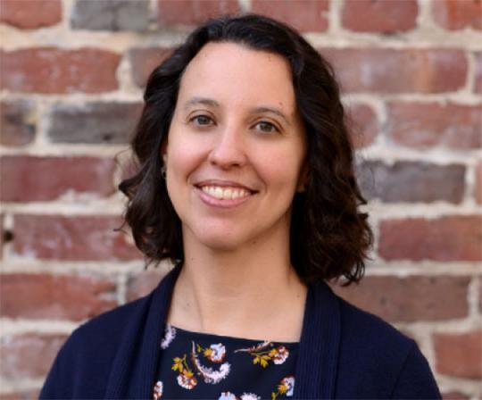 headshot of woman standing in front of brick wall