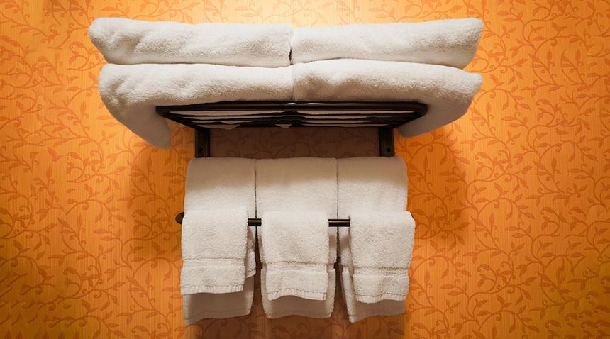 towels folded on a rack with an orange wall in the background